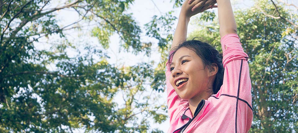 Asian young woman warm up the body stretching before morning exercise and yoga in the park under warm light morning. Healthy young asian woman exercising at park. Woman exercise outdoor concept.